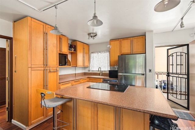 kitchen with track lighting, a kitchen bar, stainless steel appliances, dark wood-type flooring, and decorative light fixtures