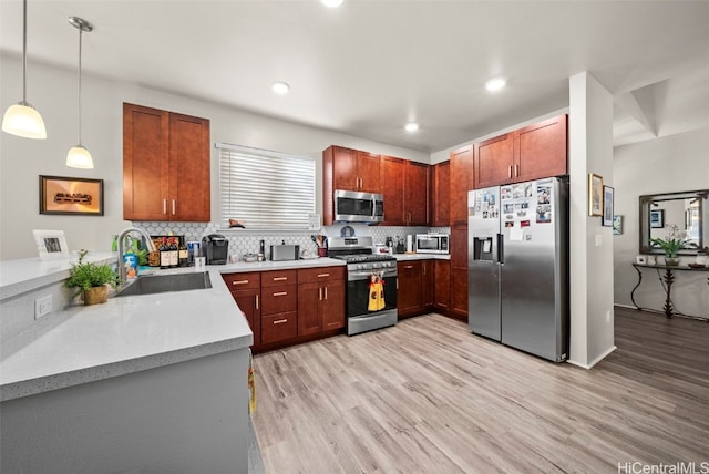 kitchen featuring pendant lighting, sink, stainless steel appliances, and light wood-type flooring