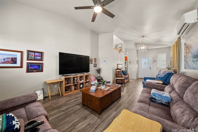 living room with dark wood-type flooring, lofted ceiling, a wall mounted air conditioner, and ceiling fan with notable chandelier