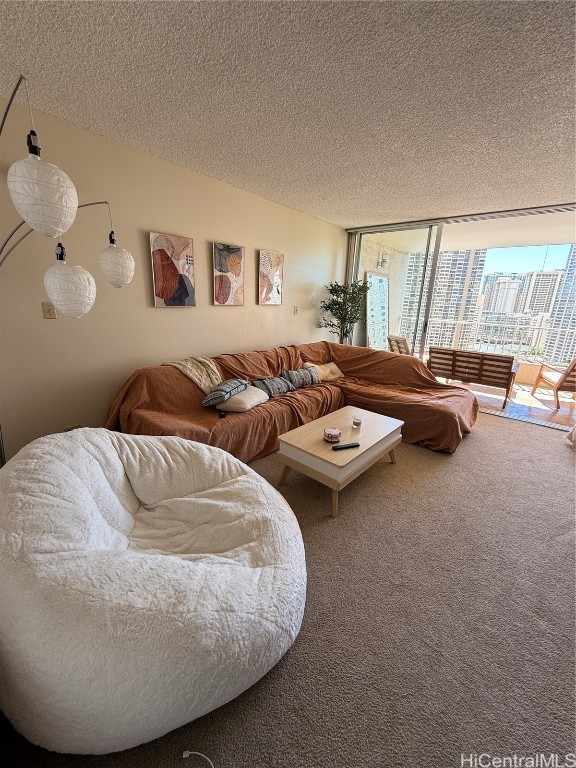 living room featuring carpet floors, a textured ceiling, and a wall of windows