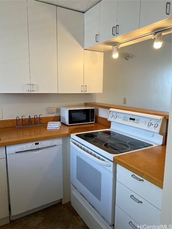 kitchen with white appliances, a textured ceiling, wooden counters, and white cabinets