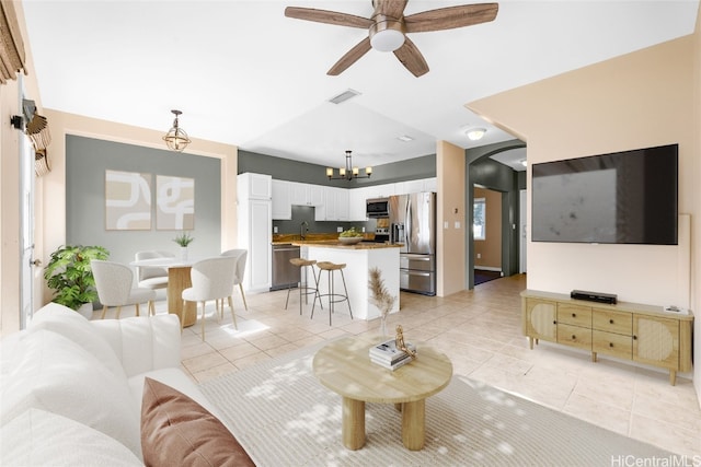 tiled living room featuring sink and ceiling fan with notable chandelier