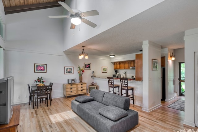 living room with light hardwood / wood-style floors, high vaulted ceiling, beamed ceiling, and ceiling fan with notable chandelier