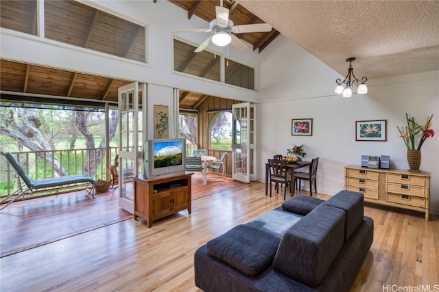 living room featuring light hardwood / wood-style flooring, ceiling fan with notable chandelier, and a wealth of natural light