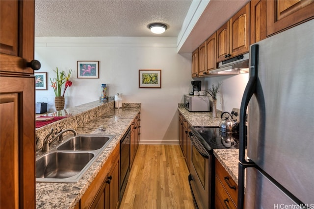 kitchen featuring a textured ceiling, stainless steel appliances, sink, and light wood-type flooring