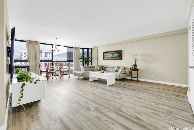 living room with light hardwood / wood-style flooring, a notable chandelier, and floor to ceiling windows