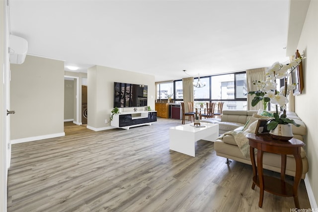 2724 Kahoaloha Ln Unit 1007, Honolulu, HI 96826 - living area with light wood-style floors, baseboards, a chandelier, expansive windows, and washer / clothes dryer