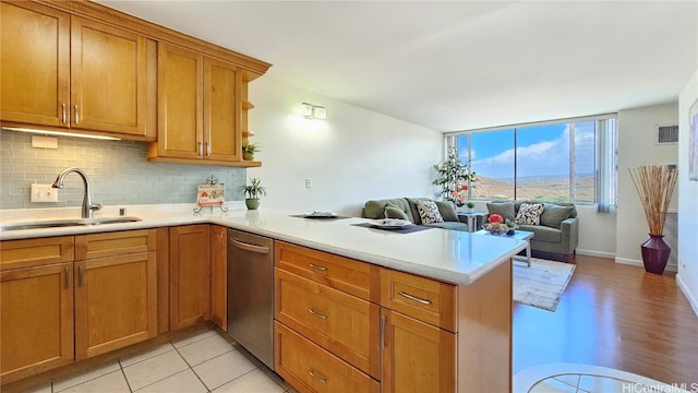 kitchen with sink, tasteful backsplash, light tile patterned floors, stainless steel dishwasher, and kitchen peninsula