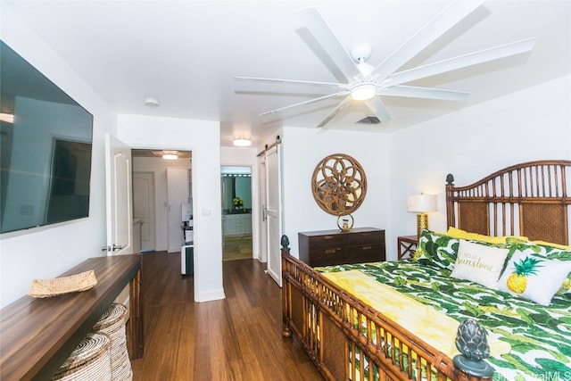 bedroom featuring ceiling fan, dark hardwood / wood-style floors, and a barn door