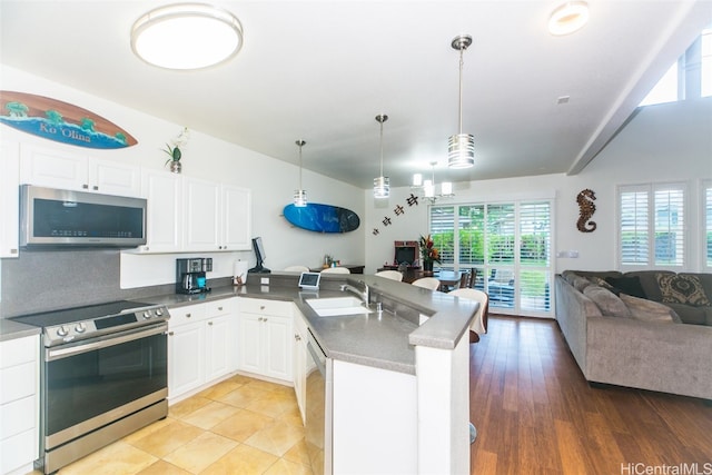 kitchen with white cabinets, hanging light fixtures, appliances with stainless steel finishes, light hardwood / wood-style flooring, and sink