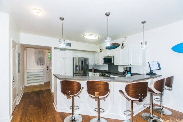 kitchen with dark wood-type flooring, white cabinets, hanging light fixtures, and stainless steel appliances