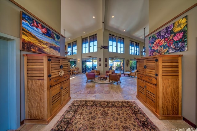 interior space with a towering ceiling and ceiling fan