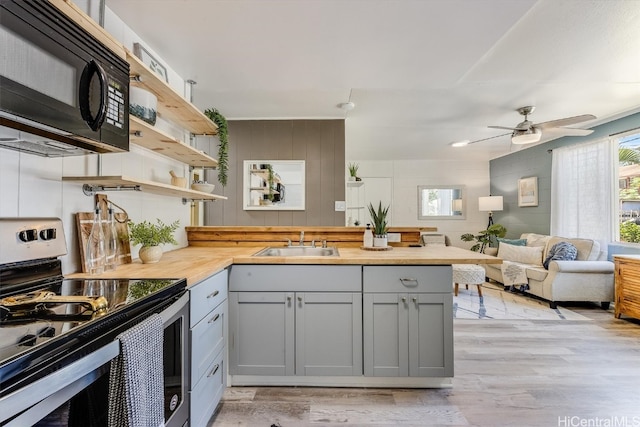 kitchen with stainless steel electric range, butcher block counters, gray cabinetry, light hardwood / wood-style floors, and sink