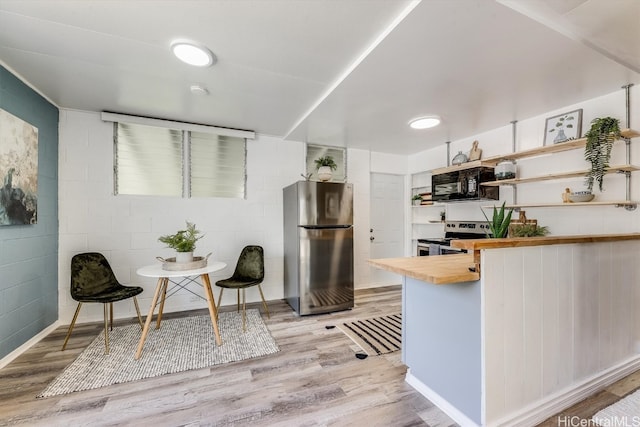 kitchen featuring light hardwood / wood-style floors, wood counters, and stainless steel appliances