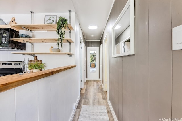 hallway featuring light hardwood / wood-style floors and wood walls