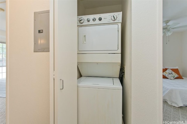 laundry area with stacked washer and dryer, electric panel, laundry area, and a ceiling fan