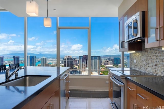 kitchen with a healthy amount of sunlight, appliances with stainless steel finishes, decorative backsplash, and hanging light fixtures