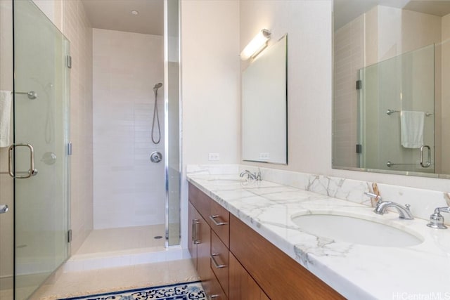 bathroom with a shower with door, vanity, and tile patterned floors