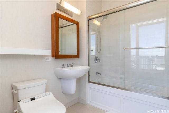 bathroom with toilet and combined bath / shower with glass door