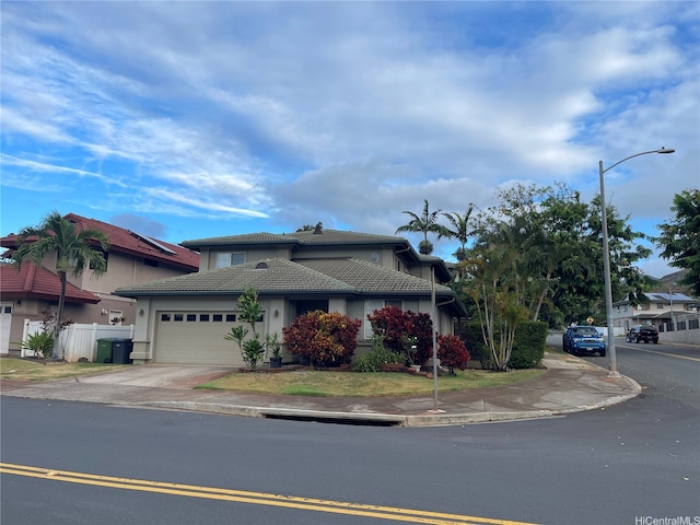 view of front of home with fence, stucco siding, an attached garage, a tile roof, and driveway