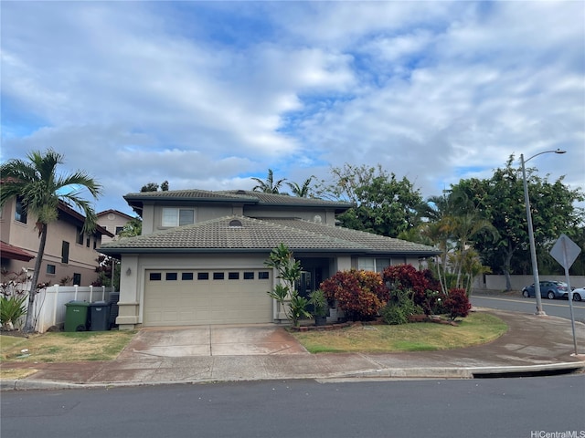 view of front of home with fence, a tiled roof, stucco siding, driveway, and a garage
