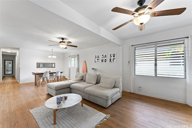 living room featuring light hardwood / wood-style floors and ceiling fan with notable chandelier