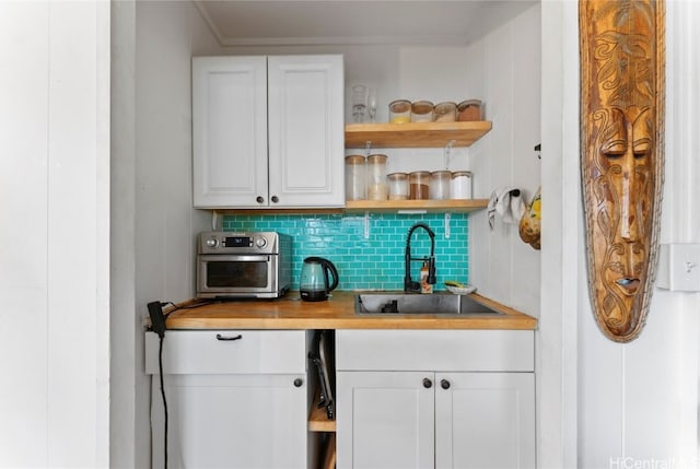 bar featuring white cabinetry, sink, wood counters, and backsplash