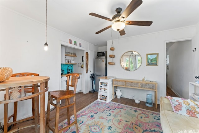 living room featuring dark wood-type flooring, ceiling fan, and ornamental molding