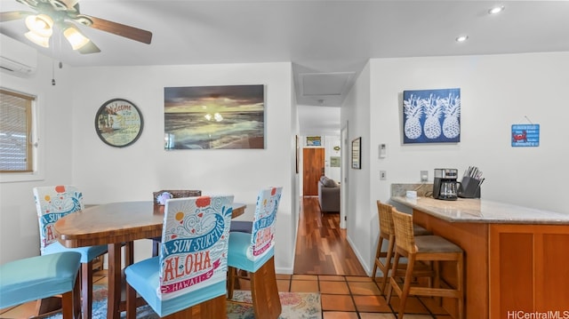 dining room with bar, a wall mounted AC, light wood-type flooring, and ceiling fan