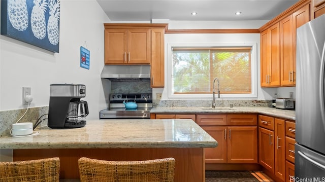 kitchen with stainless steel appliances, light stone countertops, and sink