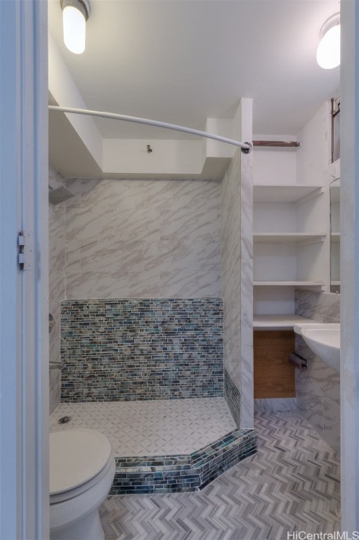 bathroom with toilet, a tile shower, and tile patterned floors