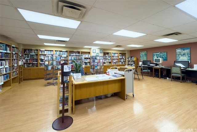 home office with a drop ceiling and light wood-type flooring