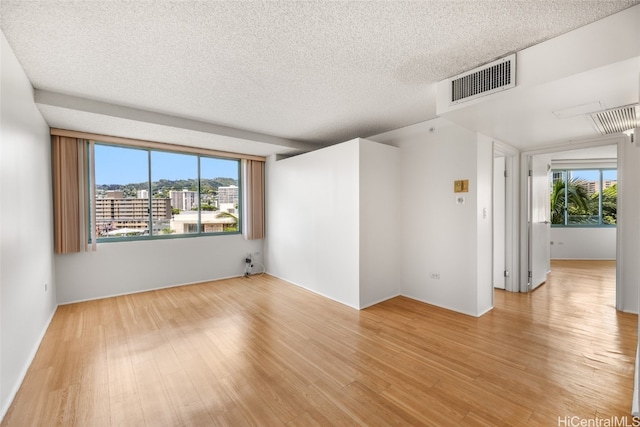 empty room featuring a textured ceiling and light hardwood / wood-style flooring