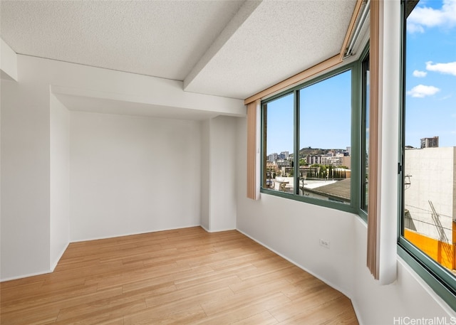 spare room featuring light hardwood / wood-style flooring and a textured ceiling