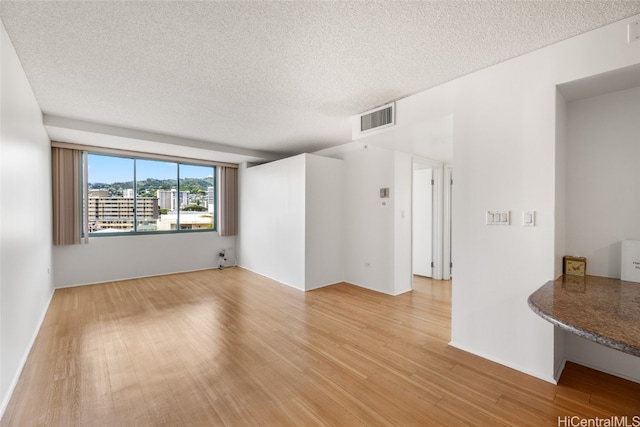 spare room with light hardwood / wood-style flooring and a textured ceiling