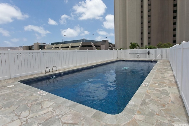community pool with a patio area and a fenced backyard