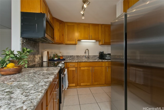 kitchen with rail lighting, sink, light tile patterned flooring, light stone counters, and stainless steel appliances