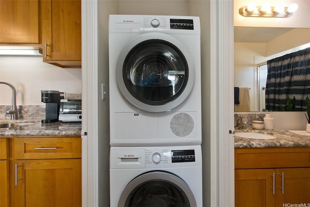 clothes washing area with stacked washer and clothes dryer, laundry area, and a sink