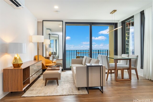 living area featuring expansive windows, hardwood / wood-style flooring, a wall mounted AC, and a water view