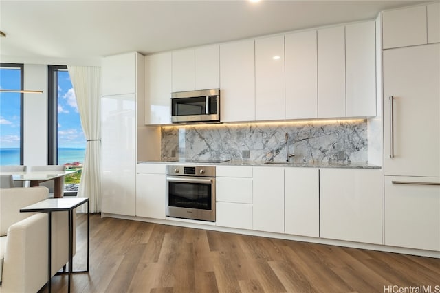 kitchen featuring white cabinets, stainless steel appliances, decorative backsplash, and wood finished floors