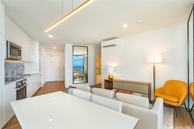 kitchen with an AC wall unit, appliances with stainless steel finishes, modern cabinets, and white cabinets