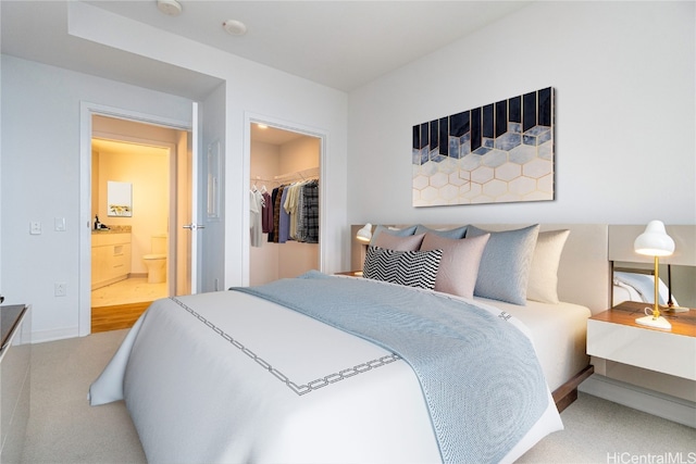 carpeted bedroom with a walk in closet, a closet, and ensuite bathroom