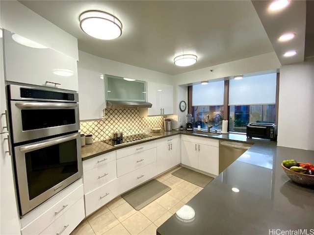 kitchen with sink, backsplash, white cabinets, and appliances with stainless steel finishes