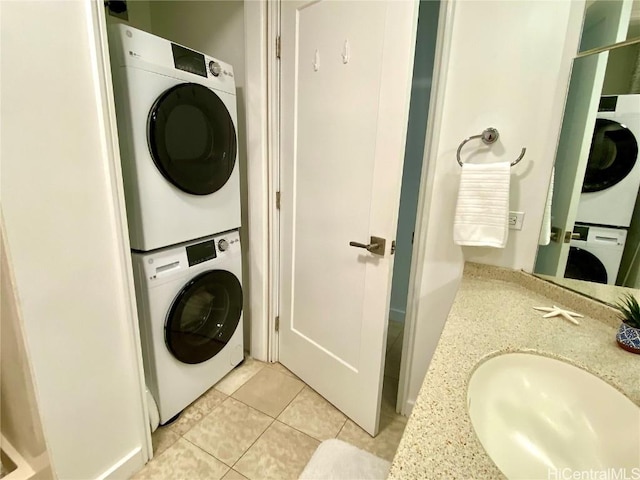 clothes washing area with stacked washing maching and dryer, sink, and light tile patterned floors