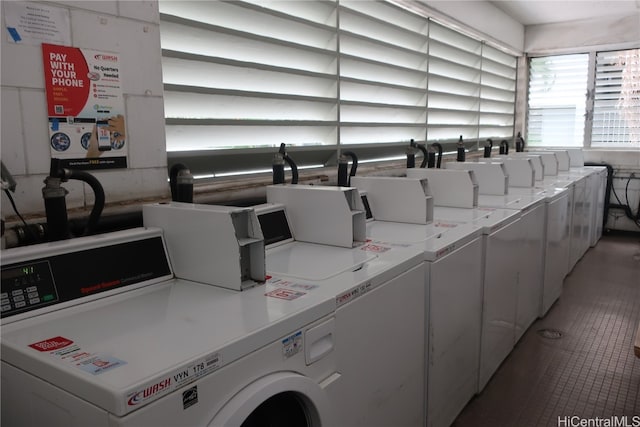 laundry area with dark tile patterned floors and washing machine and clothes dryer