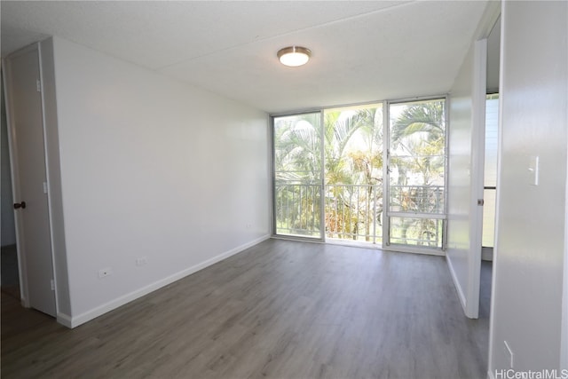 empty room with dark wood-type flooring, a textured ceiling, and expansive windows