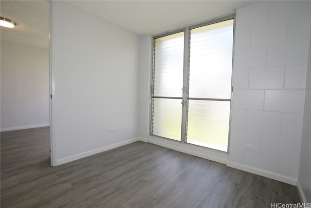 spare room featuring a textured ceiling and dark hardwood / wood-style flooring