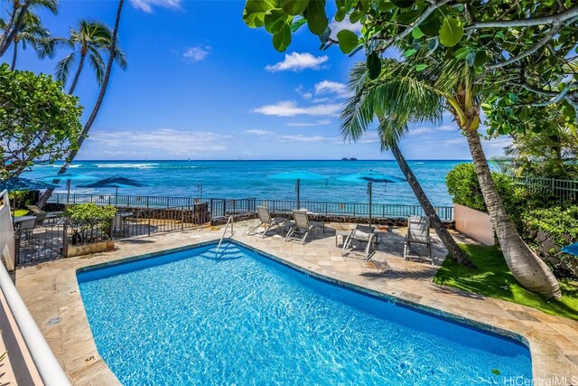 community pool featuring a water view, fence, and a patio