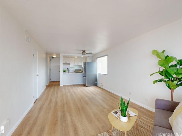 unfurnished living room featuring sink, ceiling fan, and light hardwood / wood-style flooring