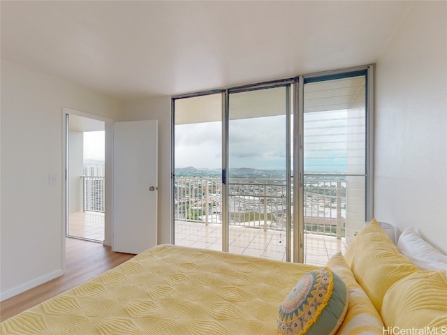 bedroom with hardwood / wood-style flooring, multiple windows, a wall of windows, and access to exterior